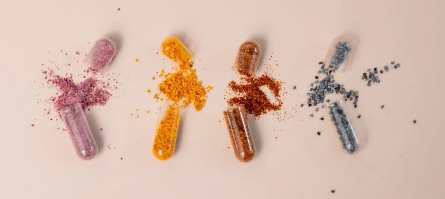 Várias vitaminas com as cápsulas abertas mostrando um pouco dos nutrientes que vai em cada cápsula.